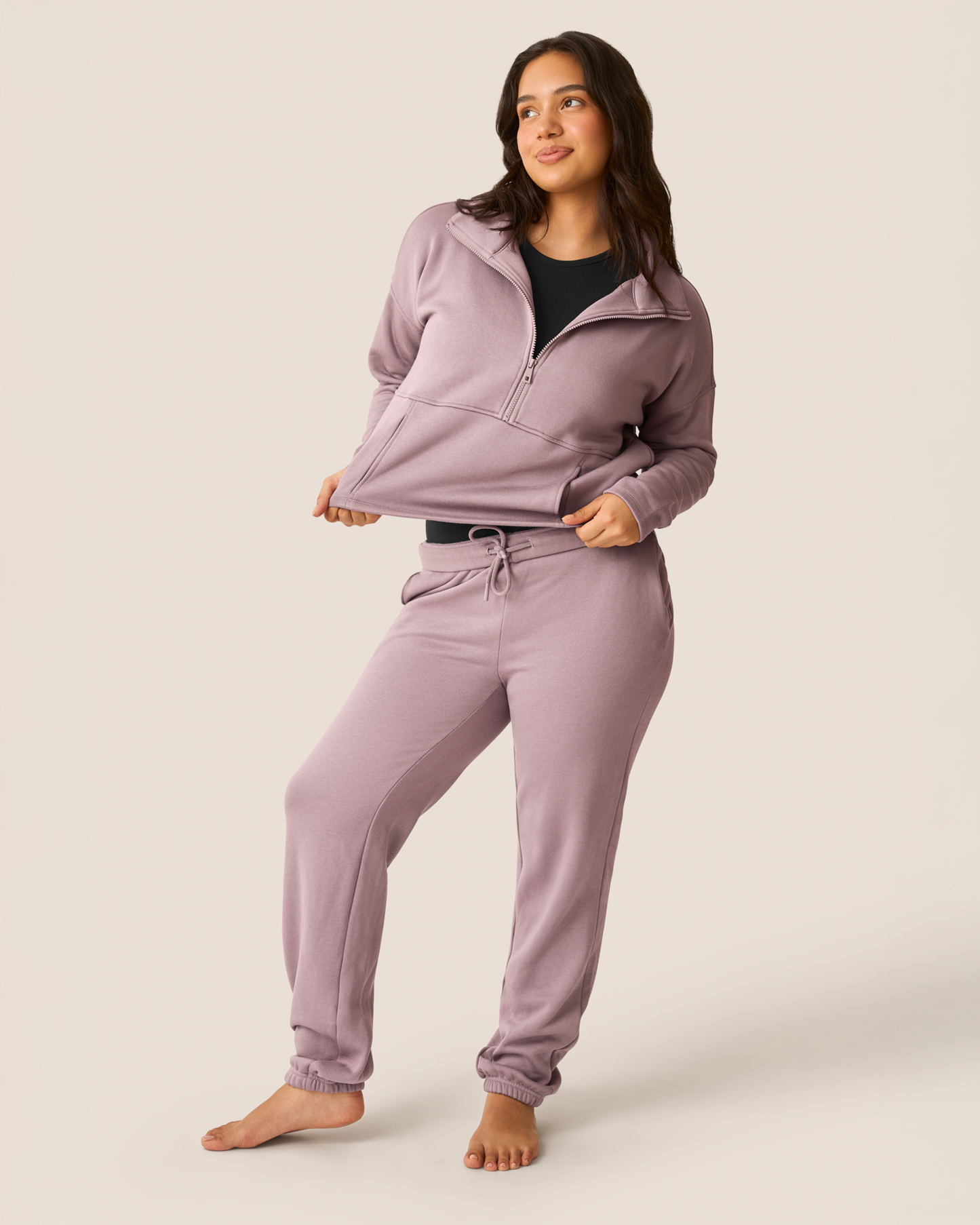 Woman wearing pieces from the Cloud Fleece collection in Dusty Mauve paired with a black tank on a beige background