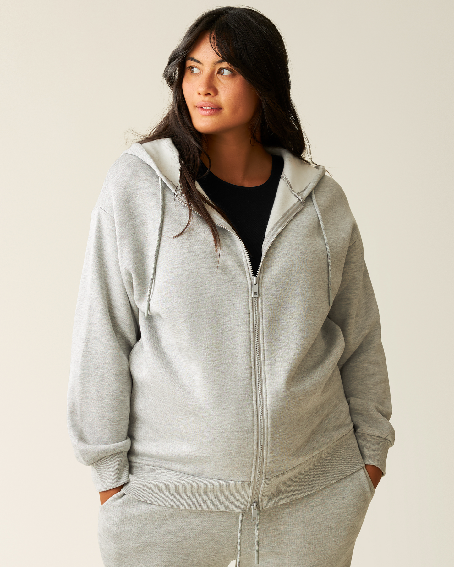 Woman wearing the Cloud Fleece Oversized Hoodie in Grey Heather  zipped up