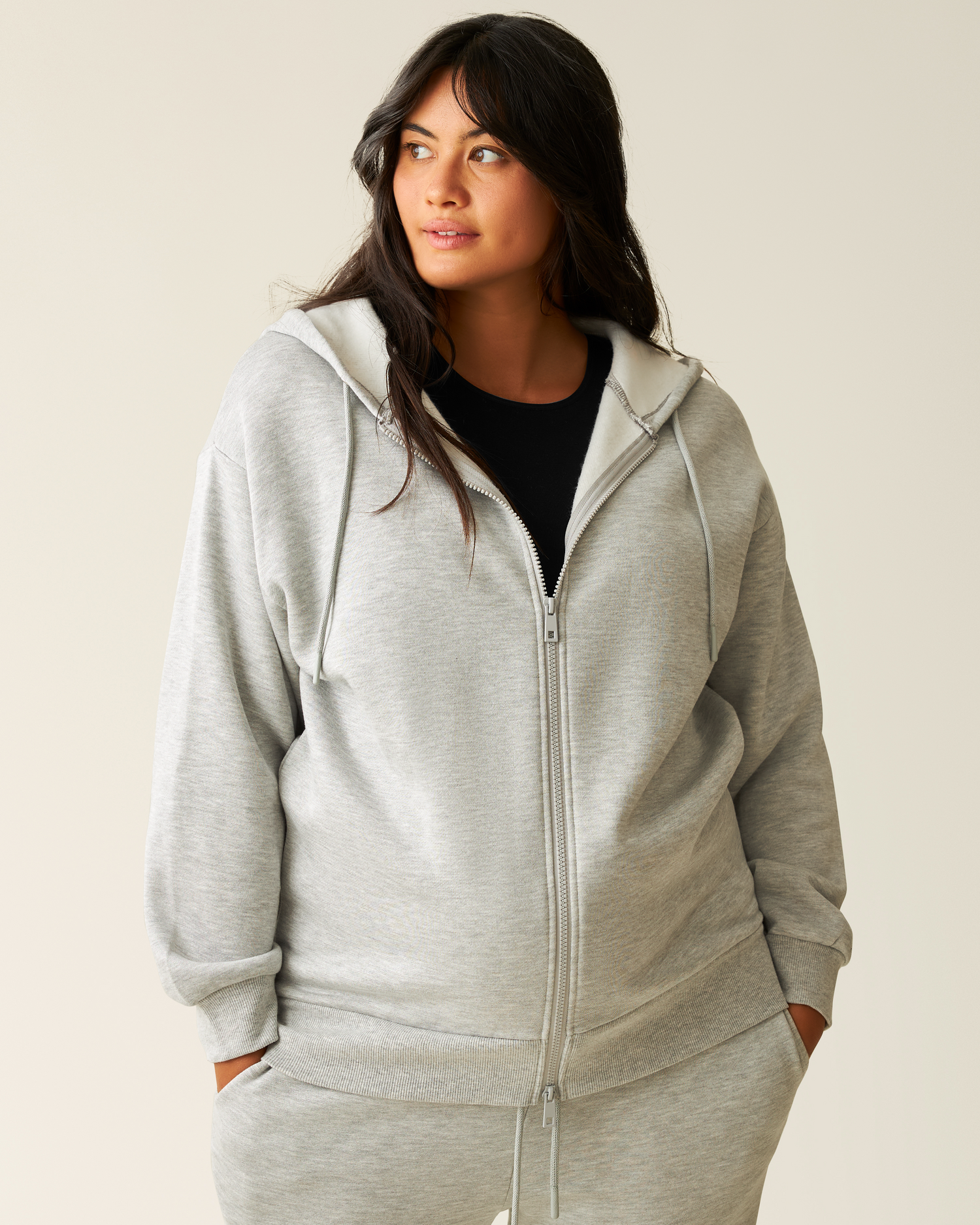 Woman wearing the Cloud Fleece Oversized Hoodie in Grey Heather  zipped up
