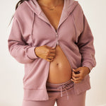 Person wearing a dusty mauve zip-up hoodie and sweatpant set on a plain background