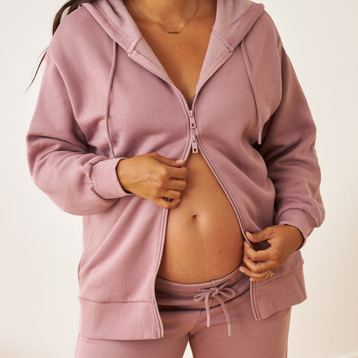Person wearing a dusty mauve zip-up hoodie and sweatpant set on a plain background