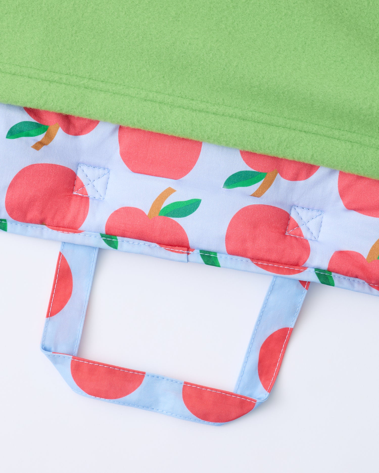 Close up of the handle and blanket of the Cool Kid Nap Mat in Blue Apple on a beige background.