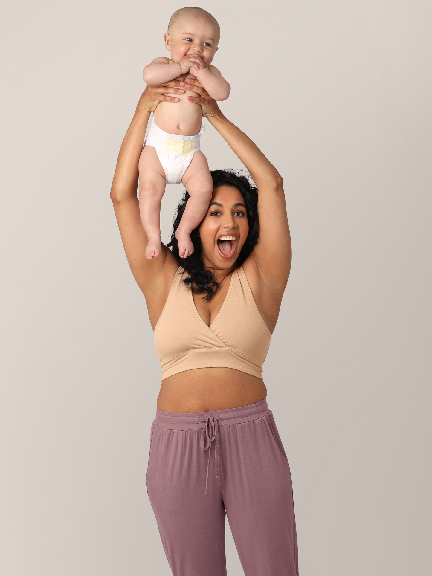 Model wearing the French Terry Nursing Bra in beige and holding her 6 month old baby