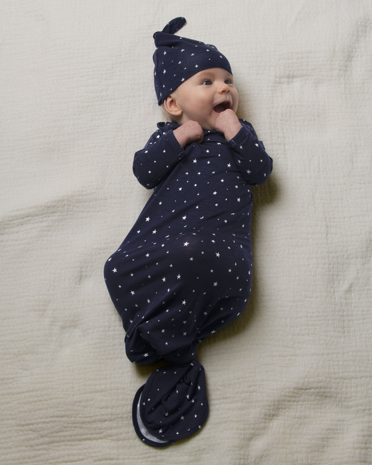 Baby wrapped in Bamboo Knotted Baby Gown in Navy Stars on a beige blanket@model_info:Danny is 3 months old.