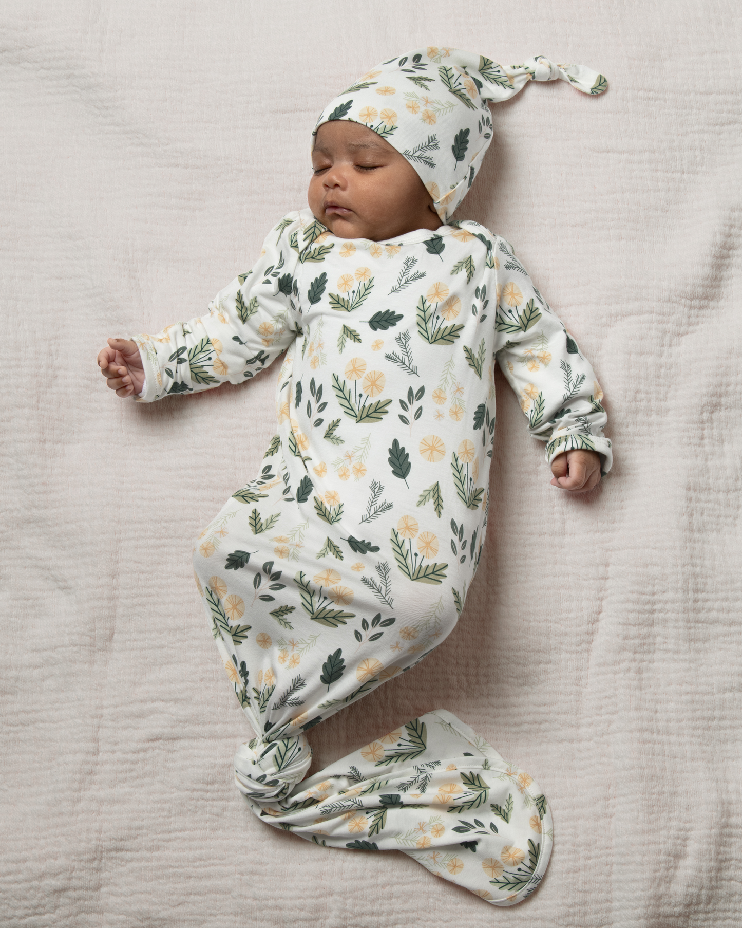 Baby wrapped in Bamboo Knotted Baby Gown in Honey Dandelion on a soft surface@model_info:Luna is 6 weeks old.