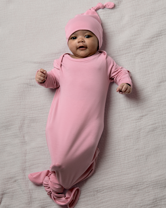 Baby in Bamboo Knotted Baby Gown in Light Mauve lying on a gray surface@model_info:Luna is 6 weeks old.