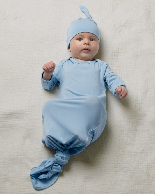 Baby in Bamboo Knotted Baby Gown in French Blue lying on a light-colored blanket@model_info:Danny is 3 months old.