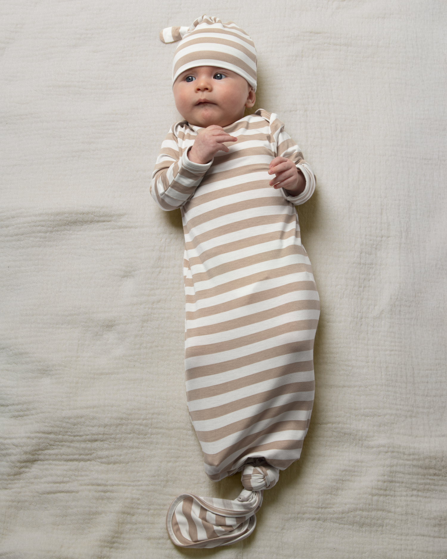 Baby wrapped in Bamboo Knotted Baby Gown in Fawn Stripe on a neutral background