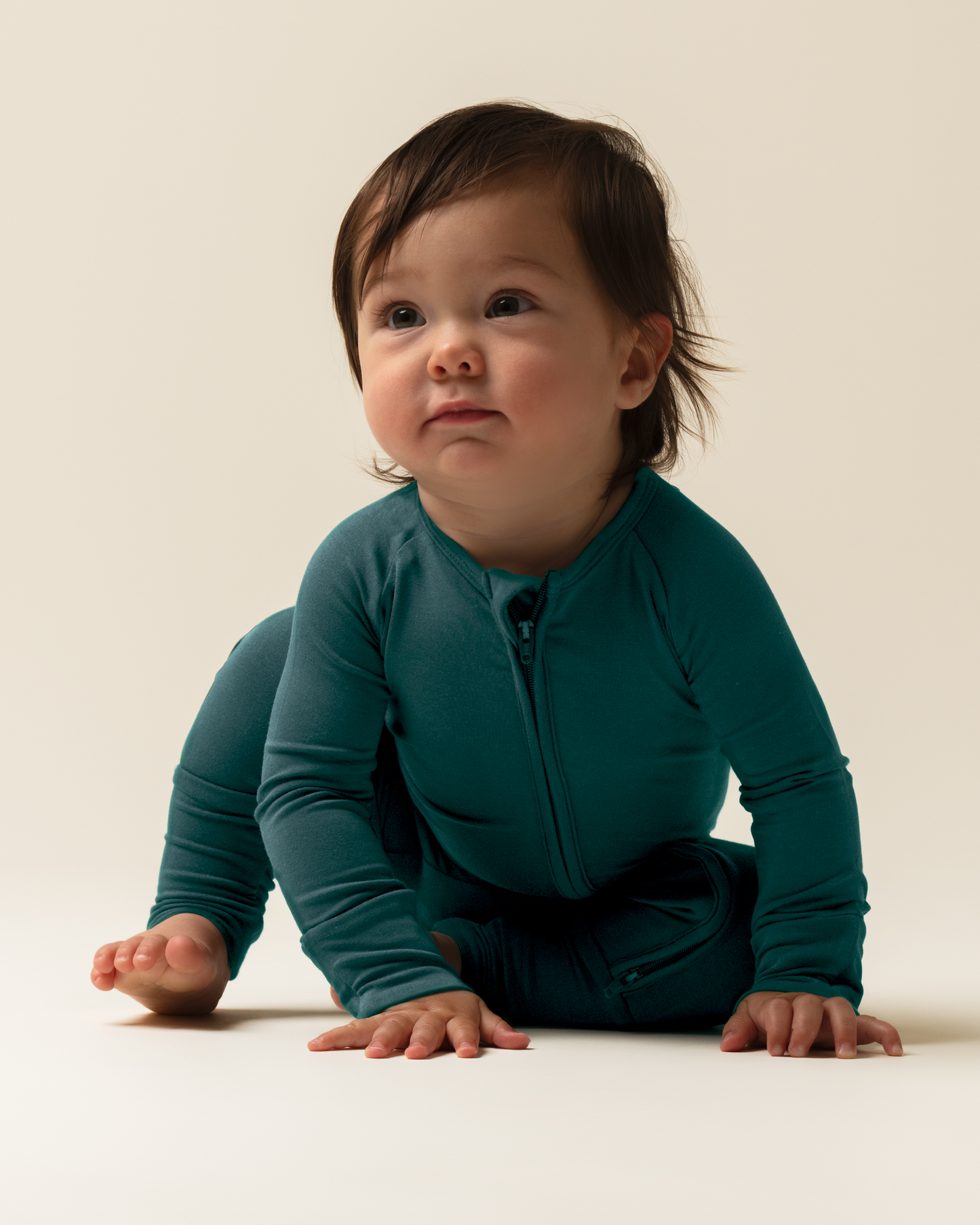 Baby wearing Bamboo Baby Pajamas in Evergreen on a plain background