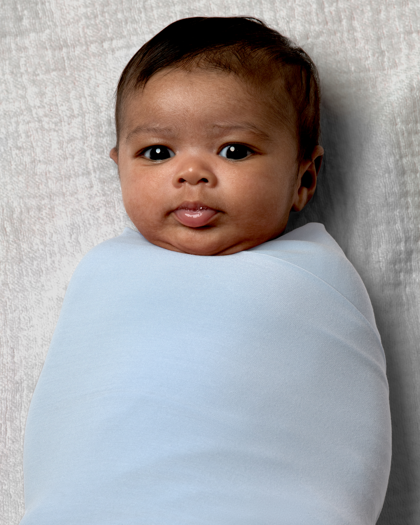 Newborn baby wrapped in Bamboo Swaddle Blanket in French Blue on a neutral background