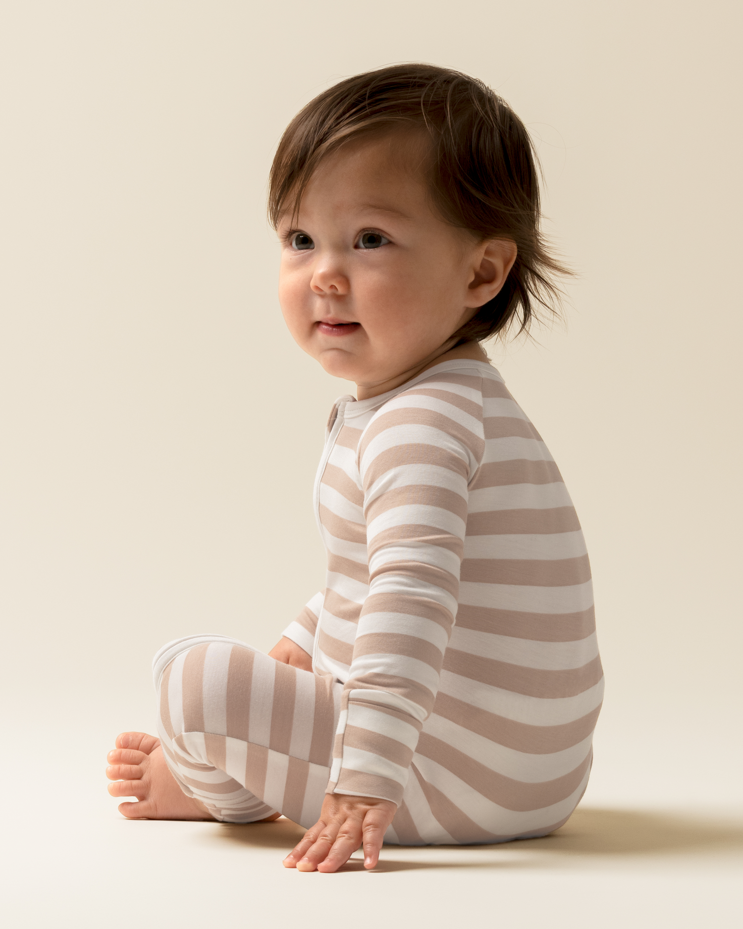 Baby wearing Bamboo Baby Pajamas in Fawn Stripe sitting on a light background