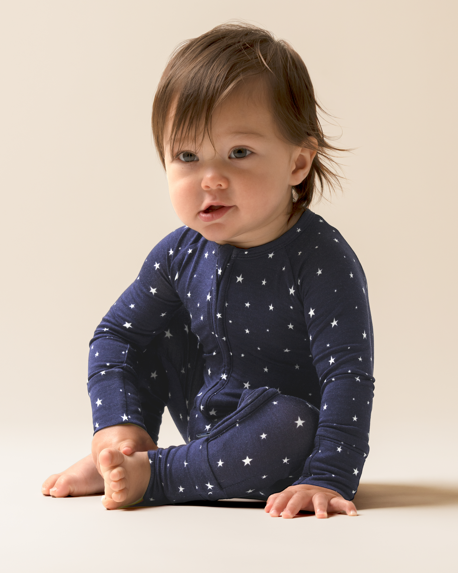 Baby wearing Bamboo Baby Pajamas in Navy Stars on a beige background