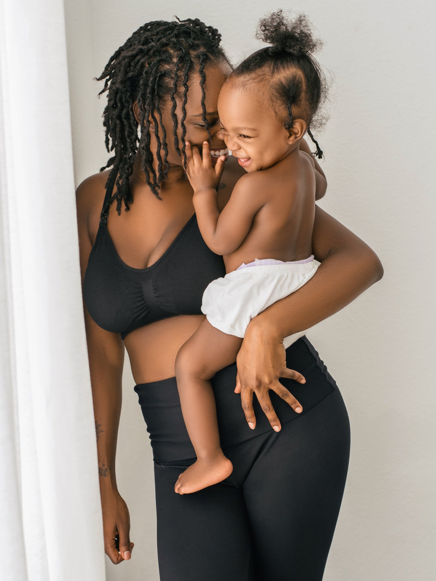 Model holding her baby while wearing the Simply Sublime® Nursing Bra in black @model_info:Adrinne is wearing a Medium.