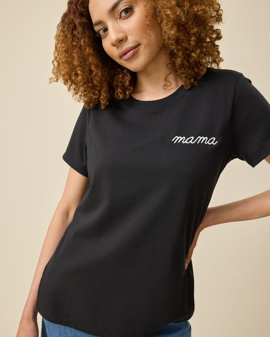 Model wearing Classic Cotton Nursing T-shirt in Black - Embroidered, with the white-threaded word, mama, on a beige background.@model_info:Devyn is wearing a Small.