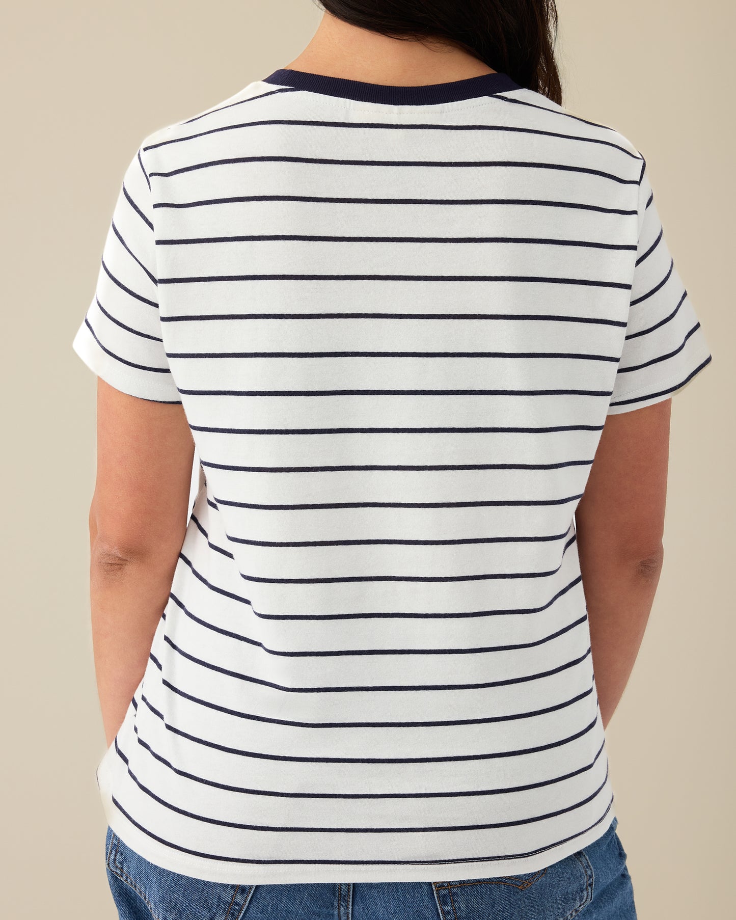Back view of Model wearing Classic Cotton Nursing T-shirt in Navy & White Stripe - Embroidered, with the red-threaded word, mama, on a beige background.