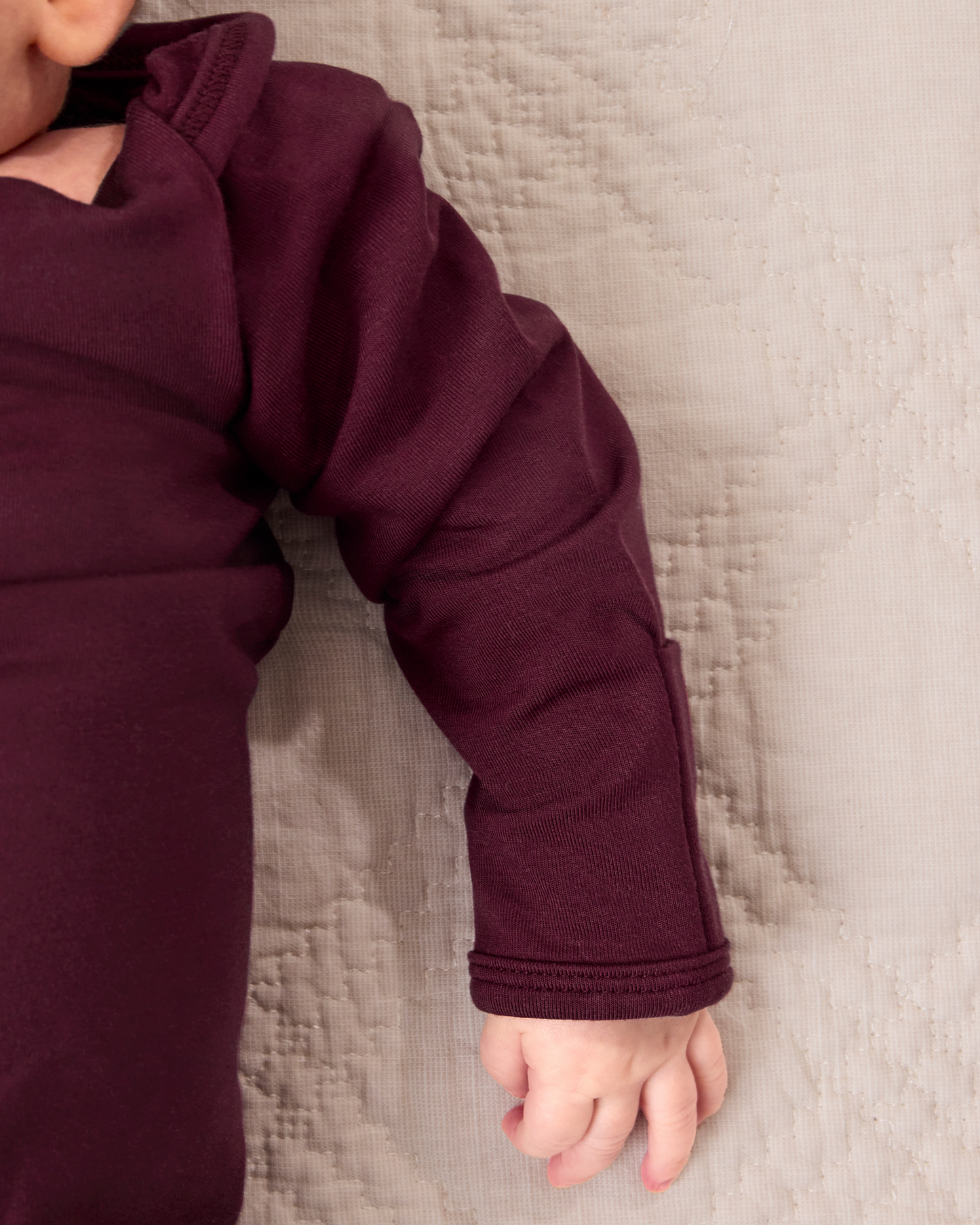 Close up of baby wearing the Cozy Bamboo Baby Gown & Hat in Deep Burgundy