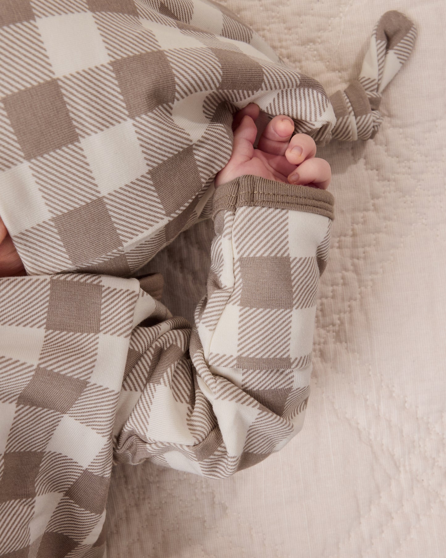 Close-up of baby wearing the Cozy Bamboo Baby Gown & Hat in Taupe Gingham checkered fabric