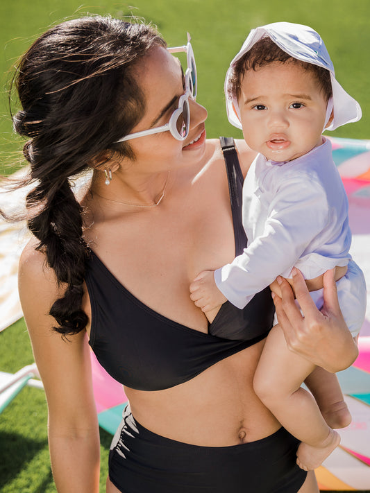 Model holding her baby while wearing the Crossover Maternity & Nursing Bikini Top @model_info:Anastacia is wearing a Small.