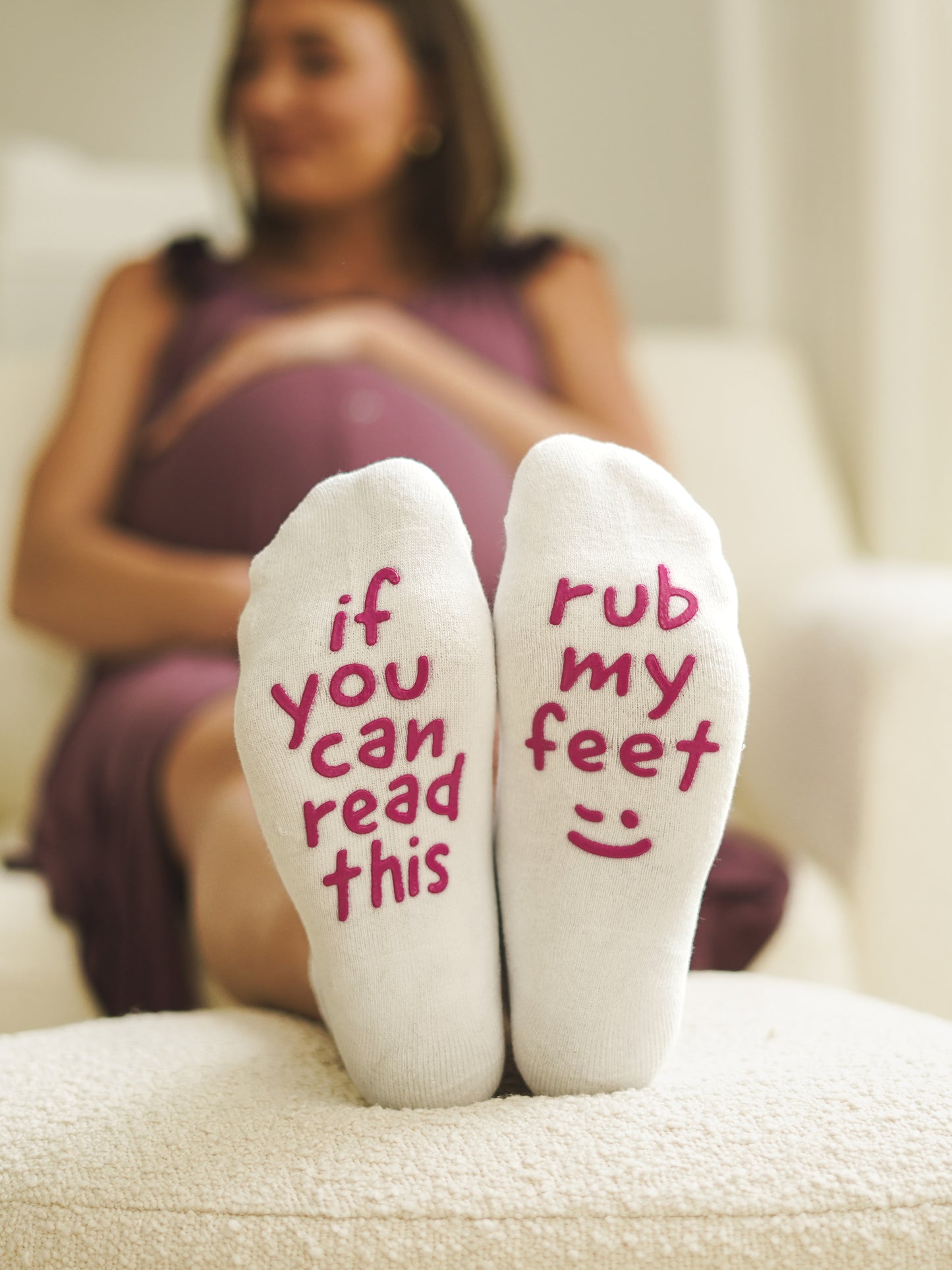 Model wearing Rub Met Feet Labor & Delivery Socks sitting on chair with feet up on ottoman
