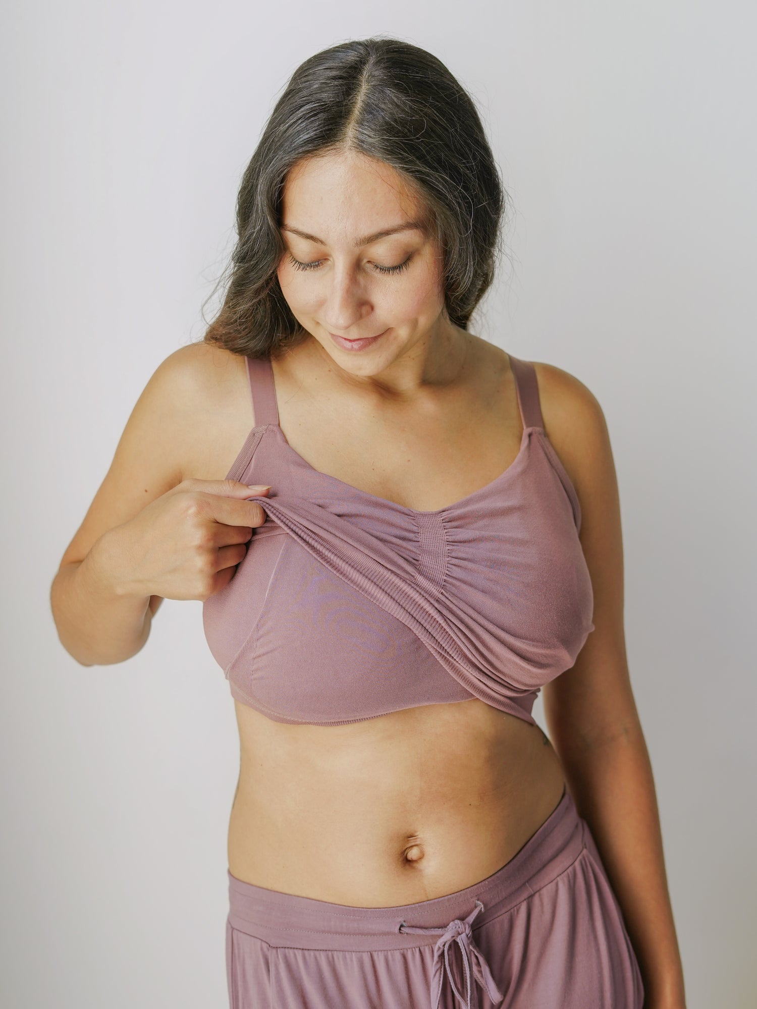 Model wearing the Sublime® Bamboo Hands-Free Pumping Lounge & Sleep Bra in Twilight, lifting outer layer to show pumping access