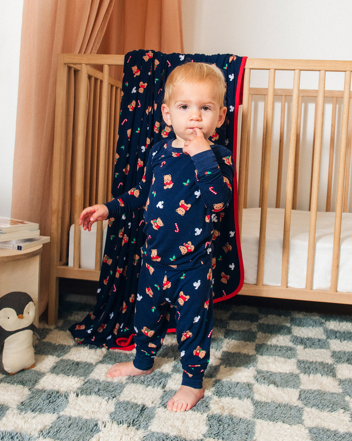 Model is wearing Bamboo Baby Two-Piece Pajama Set in Bearing Gifts nursery background with Bamboo Blanket in Bearing Gifts over the side of crib.@model_info:Rune is wearing 2T.