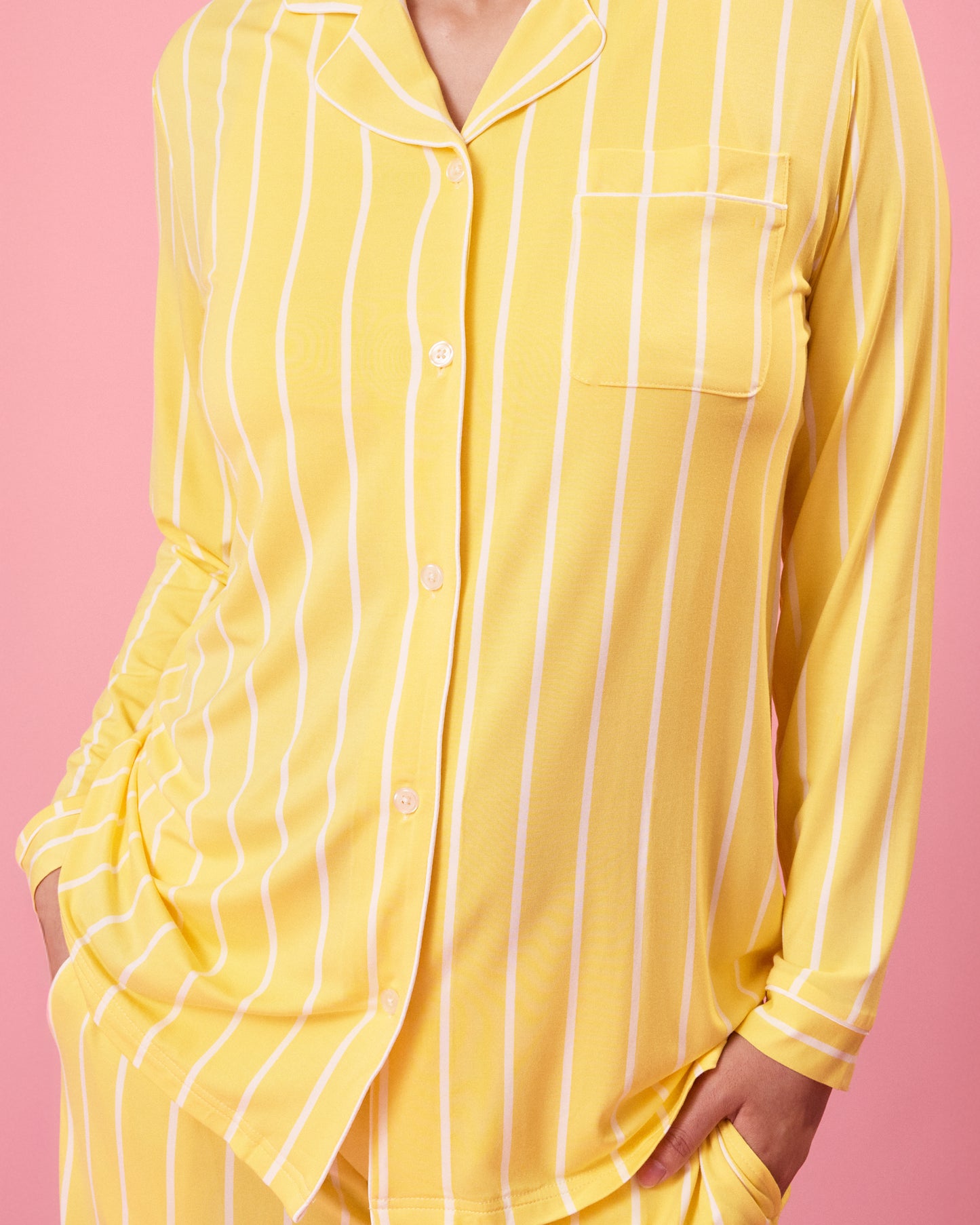 Front view of model wearing Clea Bamboo Long Sleeve Pajama Set in Dandelion Stripe on a pink background