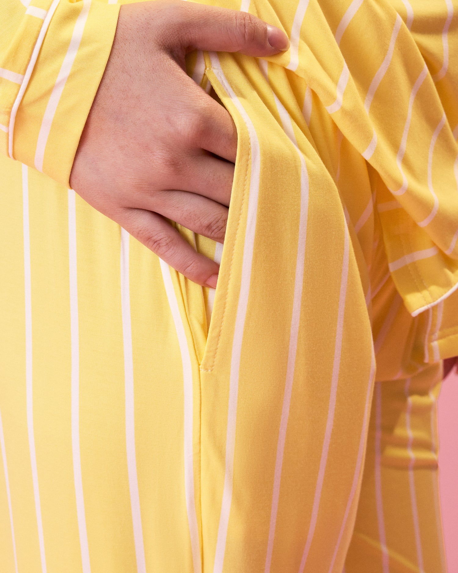 Close up of model wearing Clea Bamboo Long Sleeve Pajama Set in Dandelion Stripe showing the pockets in the set's bottoms