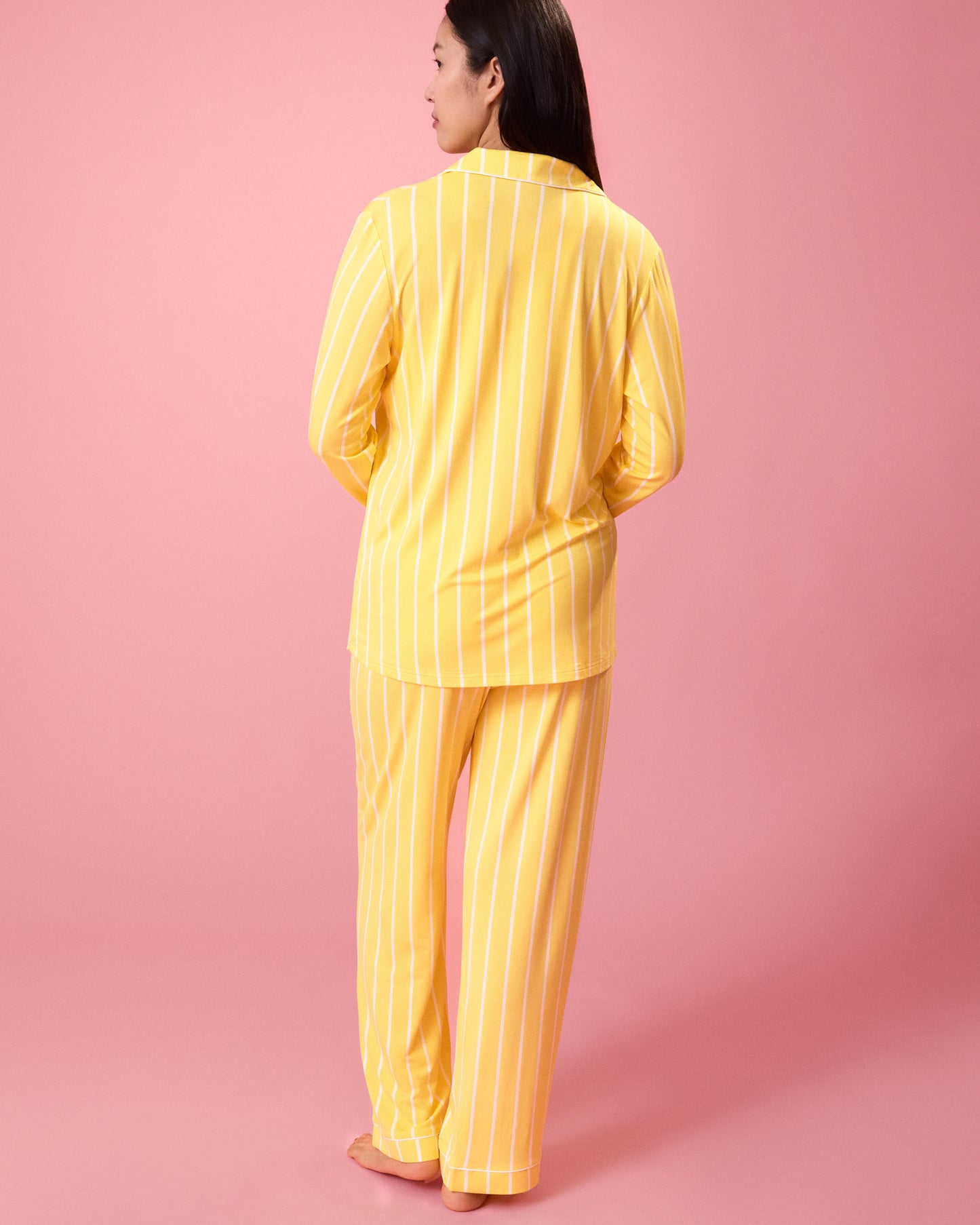 Back view of model wearing Clea Bamboo Long Sleeve Pajama Set in Dandelion Stripe on a pink background