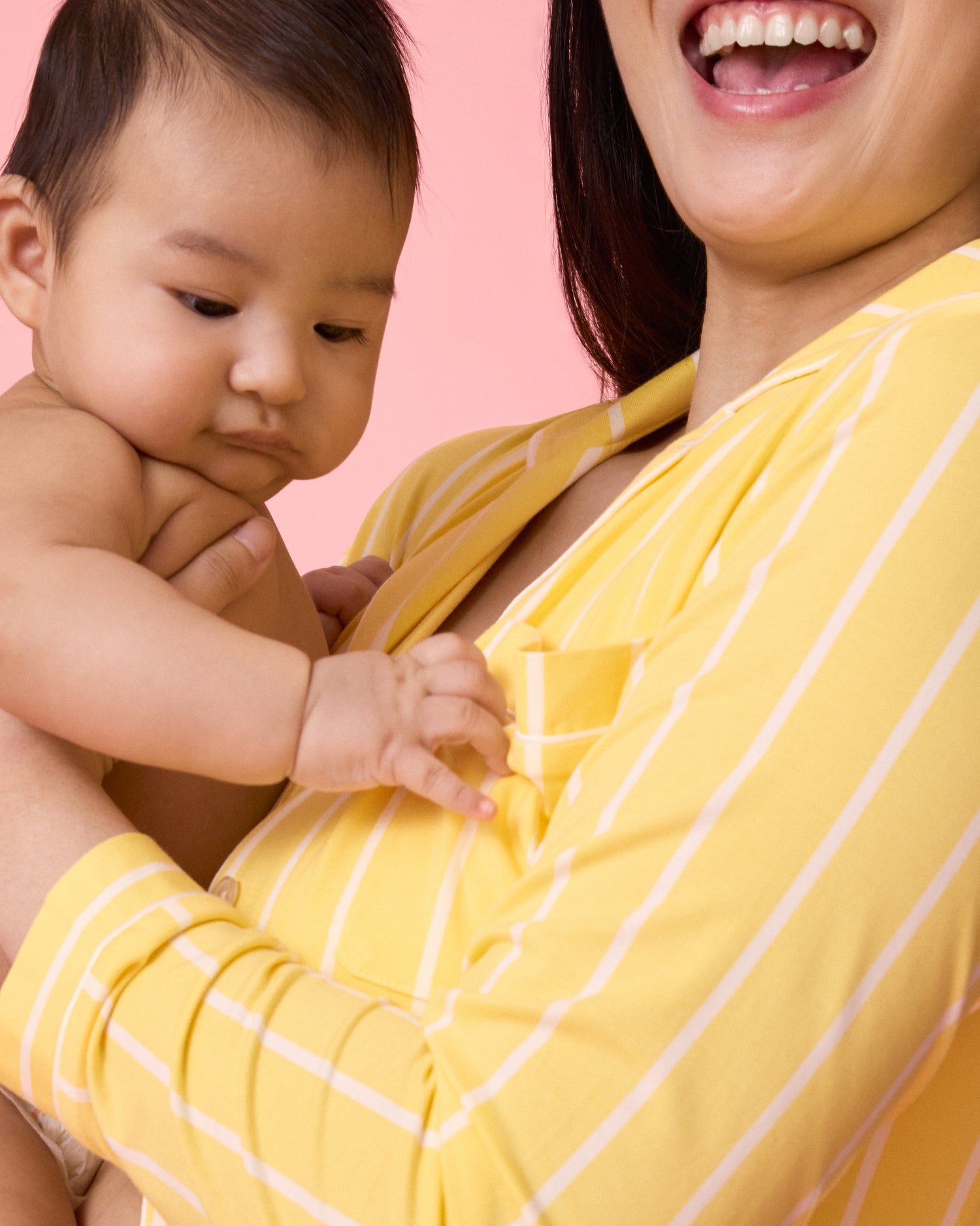 Close up of model wearing Clea Bamboo Long Sleeve Pajama Set in Dandelion Stripe laughing happily while holding a baby
