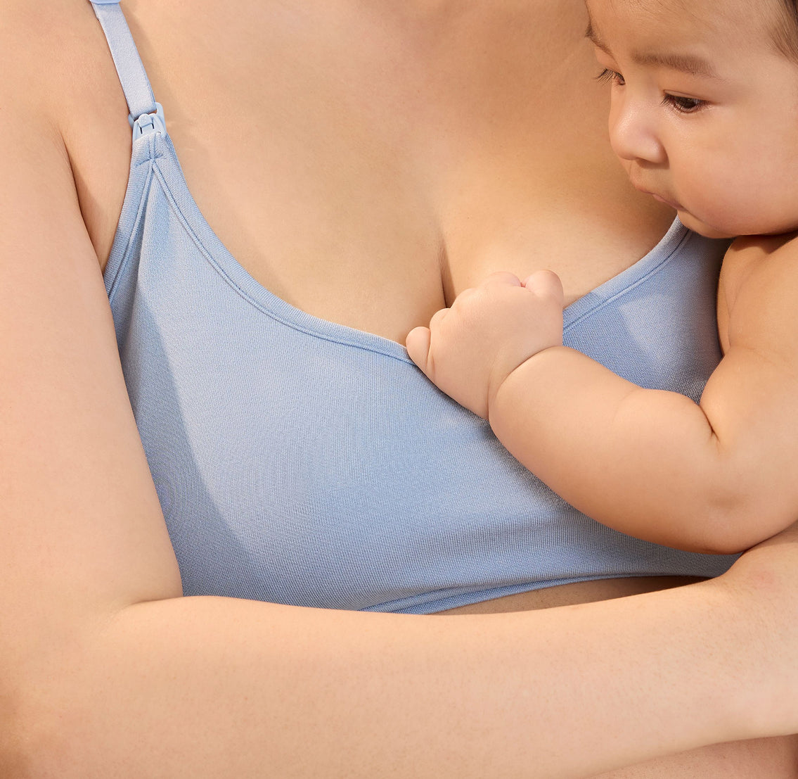 Close up of model holding a baby and wearing French Terry Maternity & Nursing Bralette in Vintage Blue