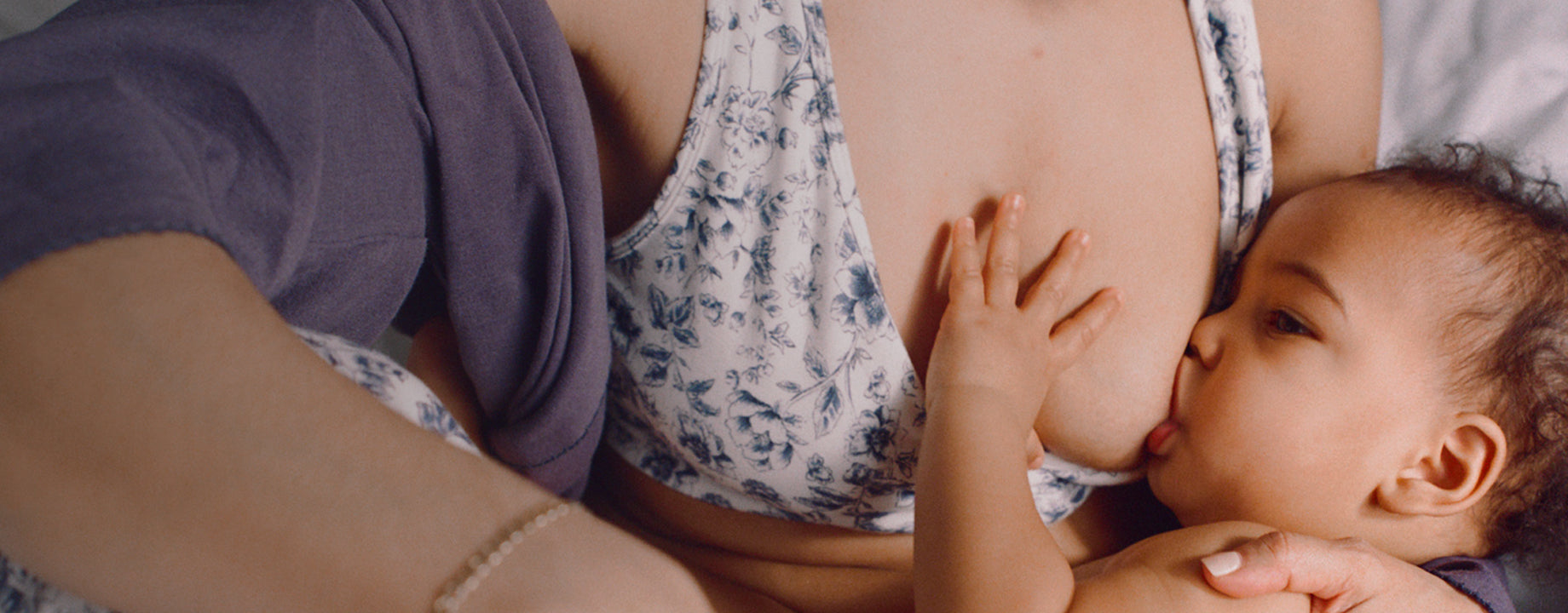 A mother breastfeeding a baby while wearing French Terry Racerback Nursing & Sleep Bra in Navy Toile with matching pajama pants with shadows on white background