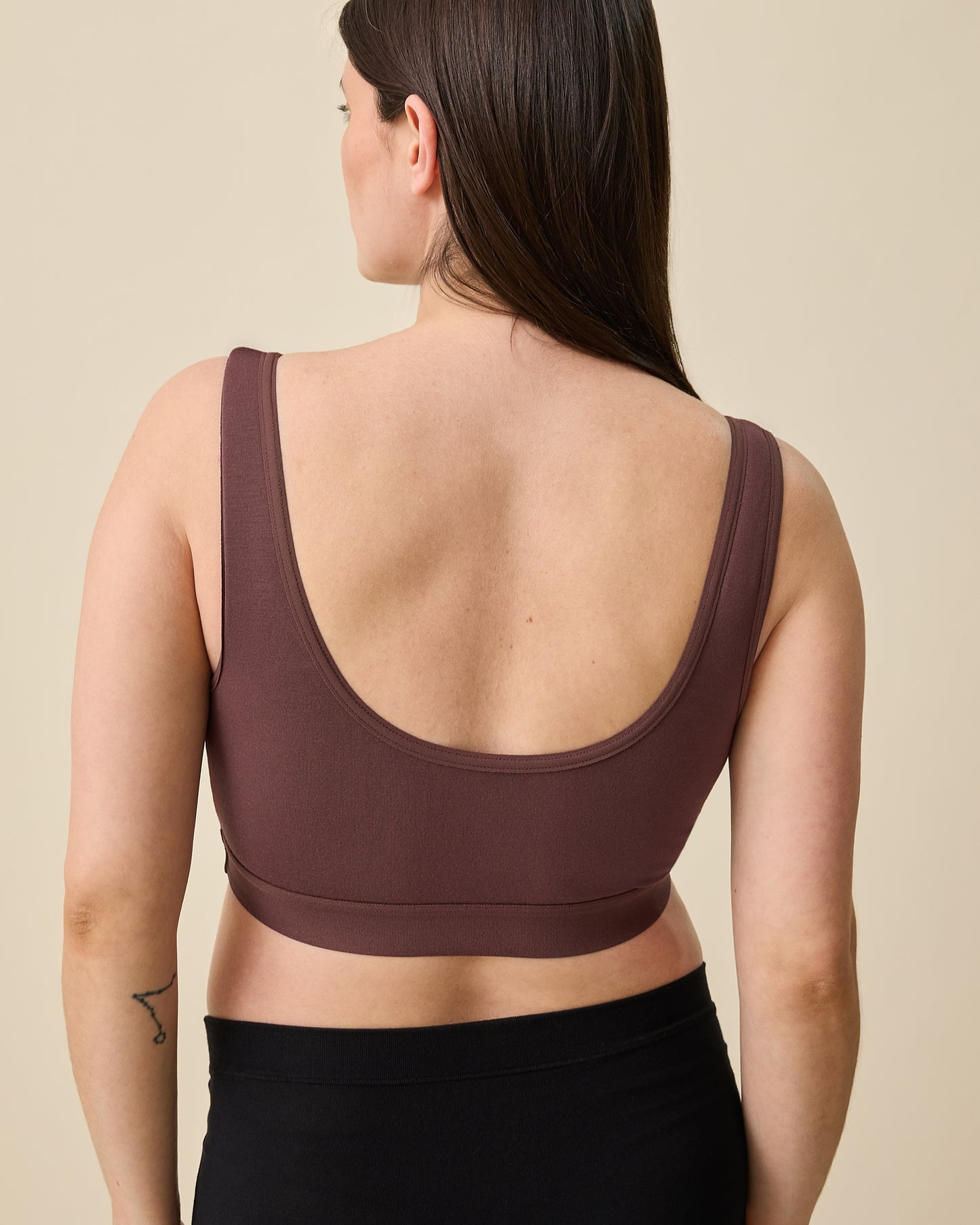 Back view of model wearing Every Stage Crossover Bra in Cocoa on a beige background