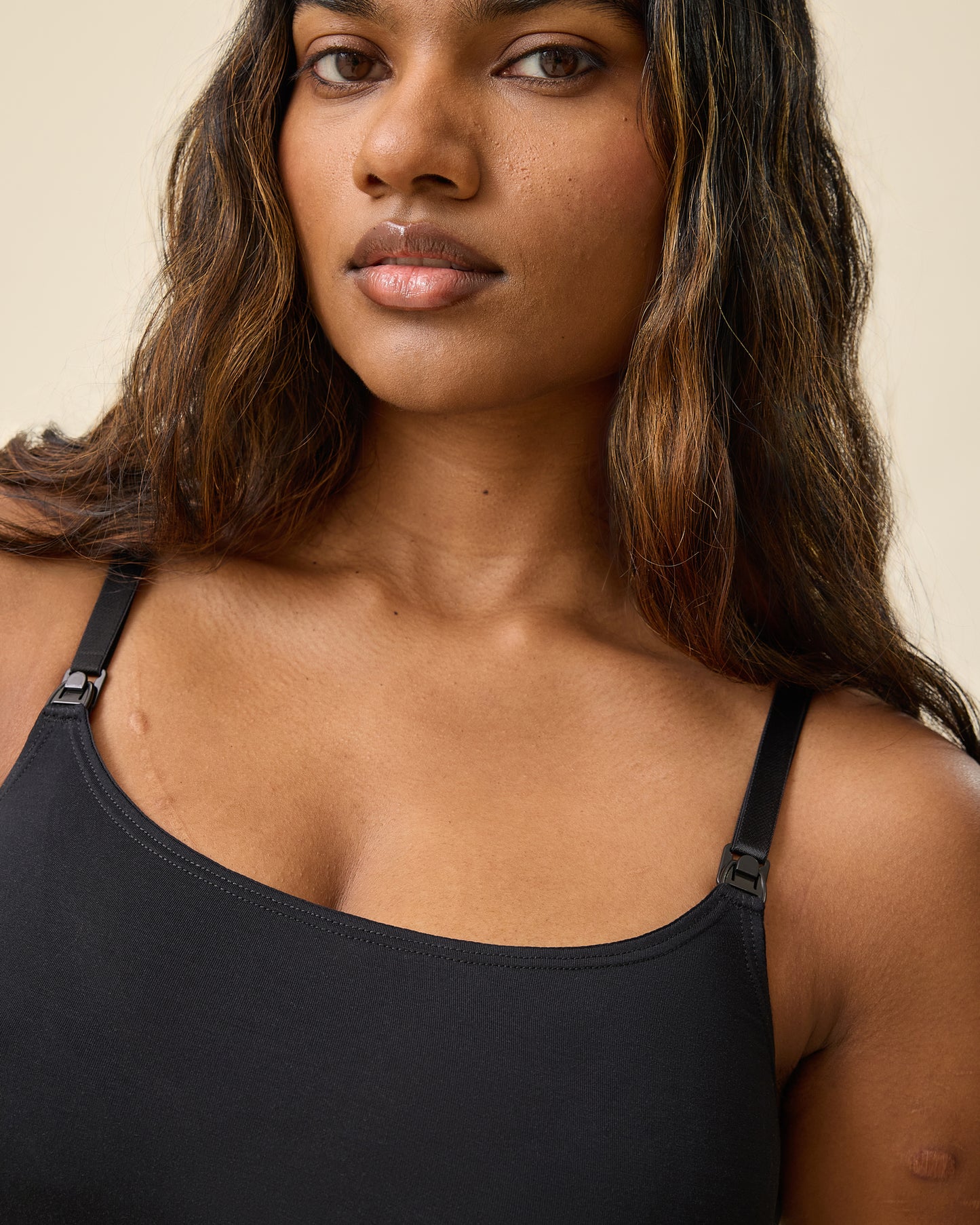 Close up of nursing clasp on Every Stage Pumping & Nursing Bra in Black on a beige background