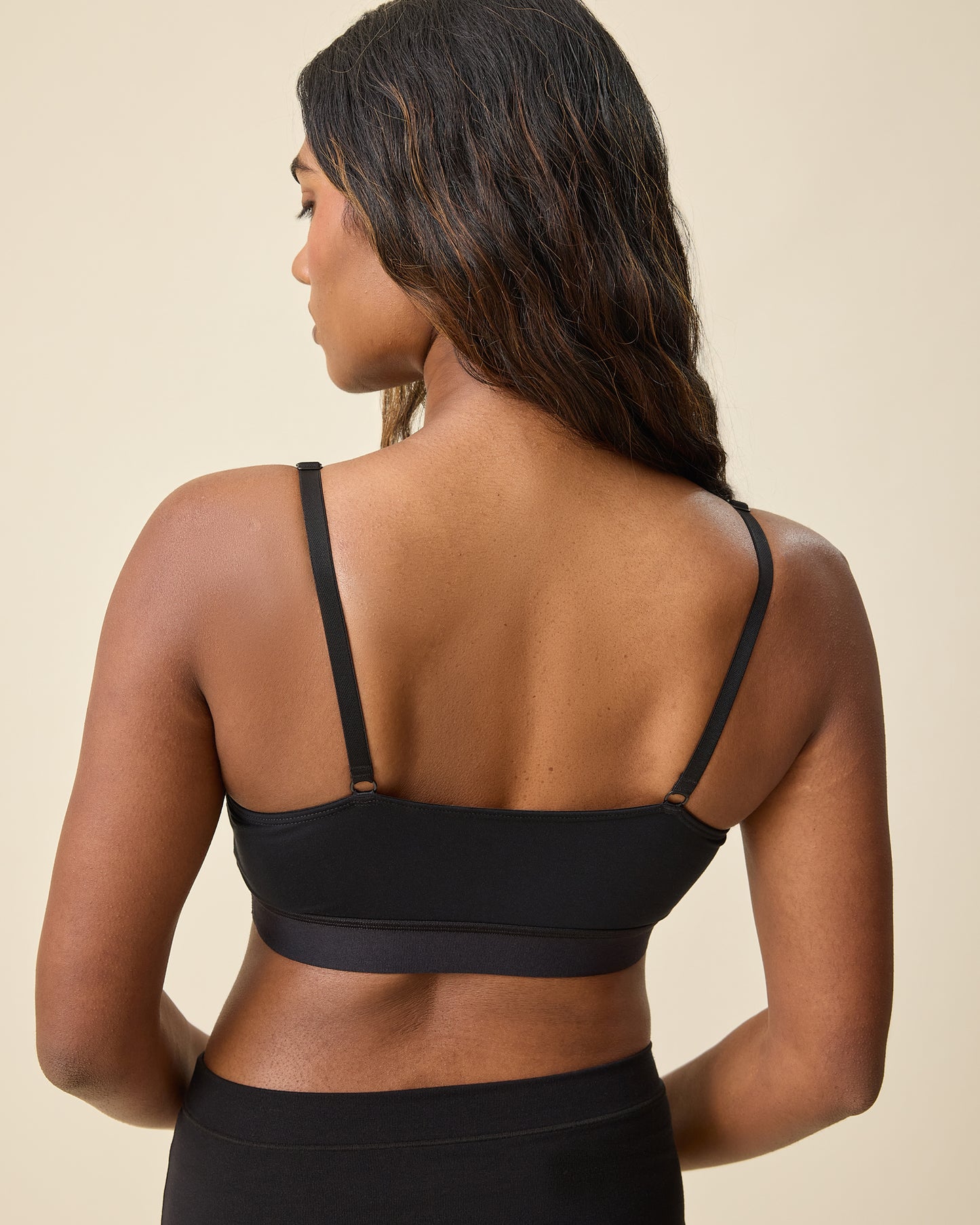 Back view of model wearing Every Stage Pumping & Nursing Bra in Black on a beige background