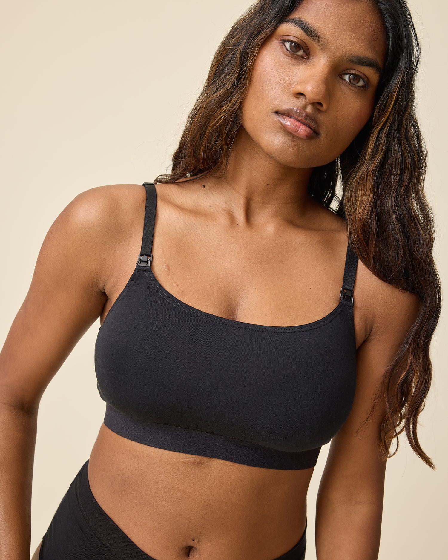 Model wearing Every Stage Pumping & Nursing Bra in Black on a beige background @model_info:Sahana is wearing a Small.