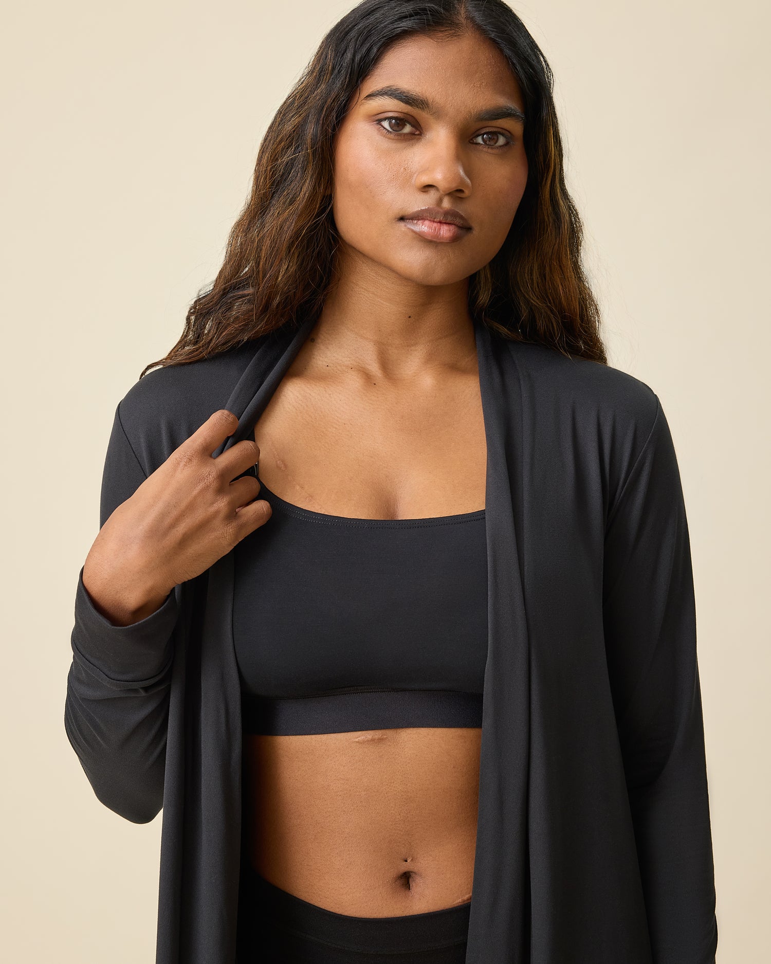 Model is wearing Every Stage Pumping & Nursing Bra and Every Stage Briefs in Black on a beige background