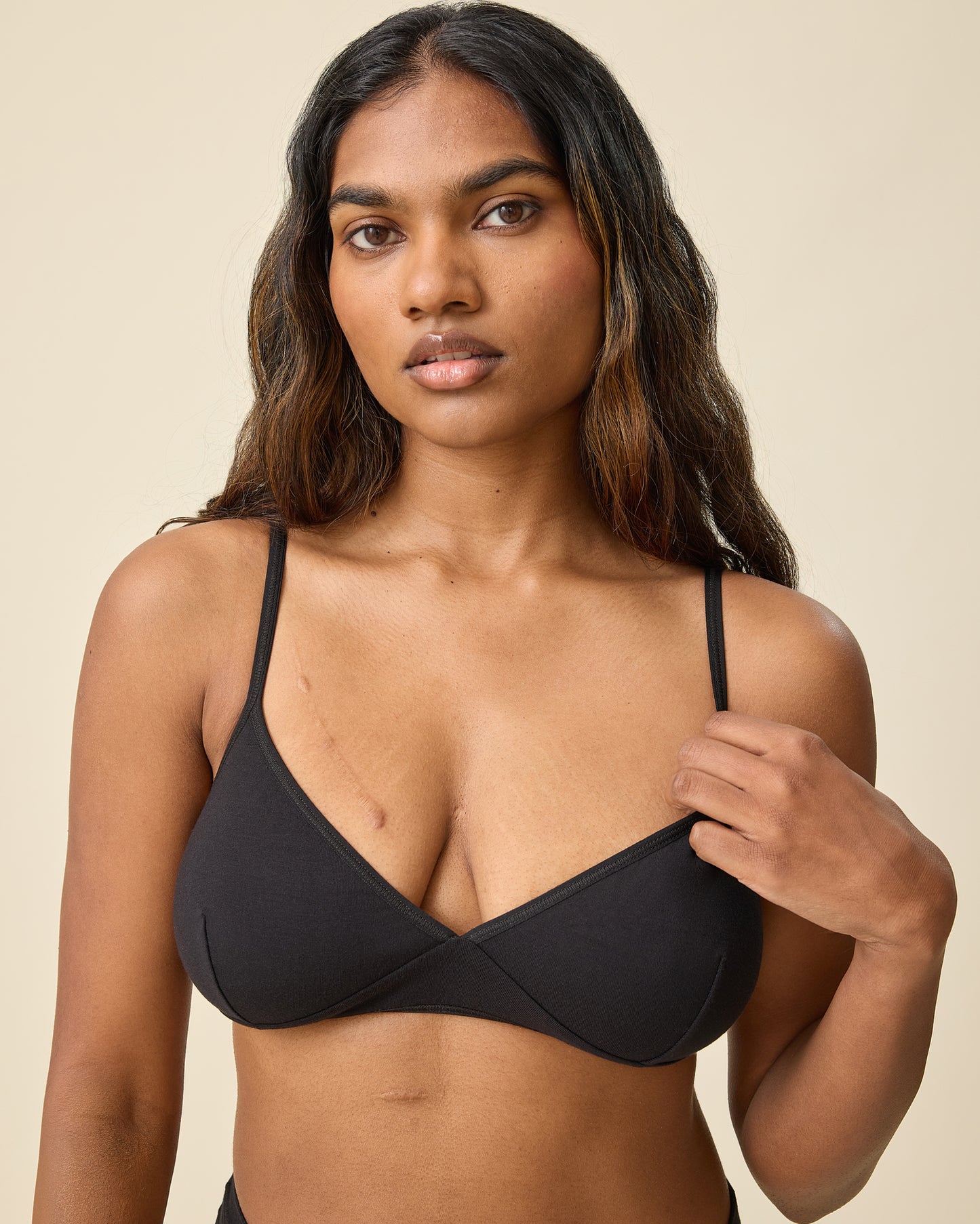Model wearing Every Stage Triangle Bralette in Black on a beige background