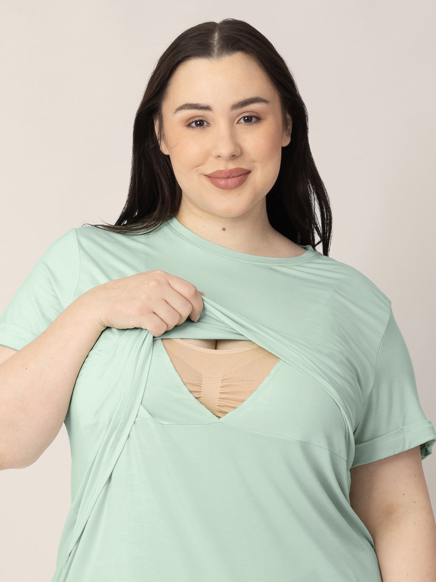 Model wearing the Everyday Asymmetrical Nursing T-shirt in Soft Mint and showing the pull aside nursing panel for easy breastfeeding access.