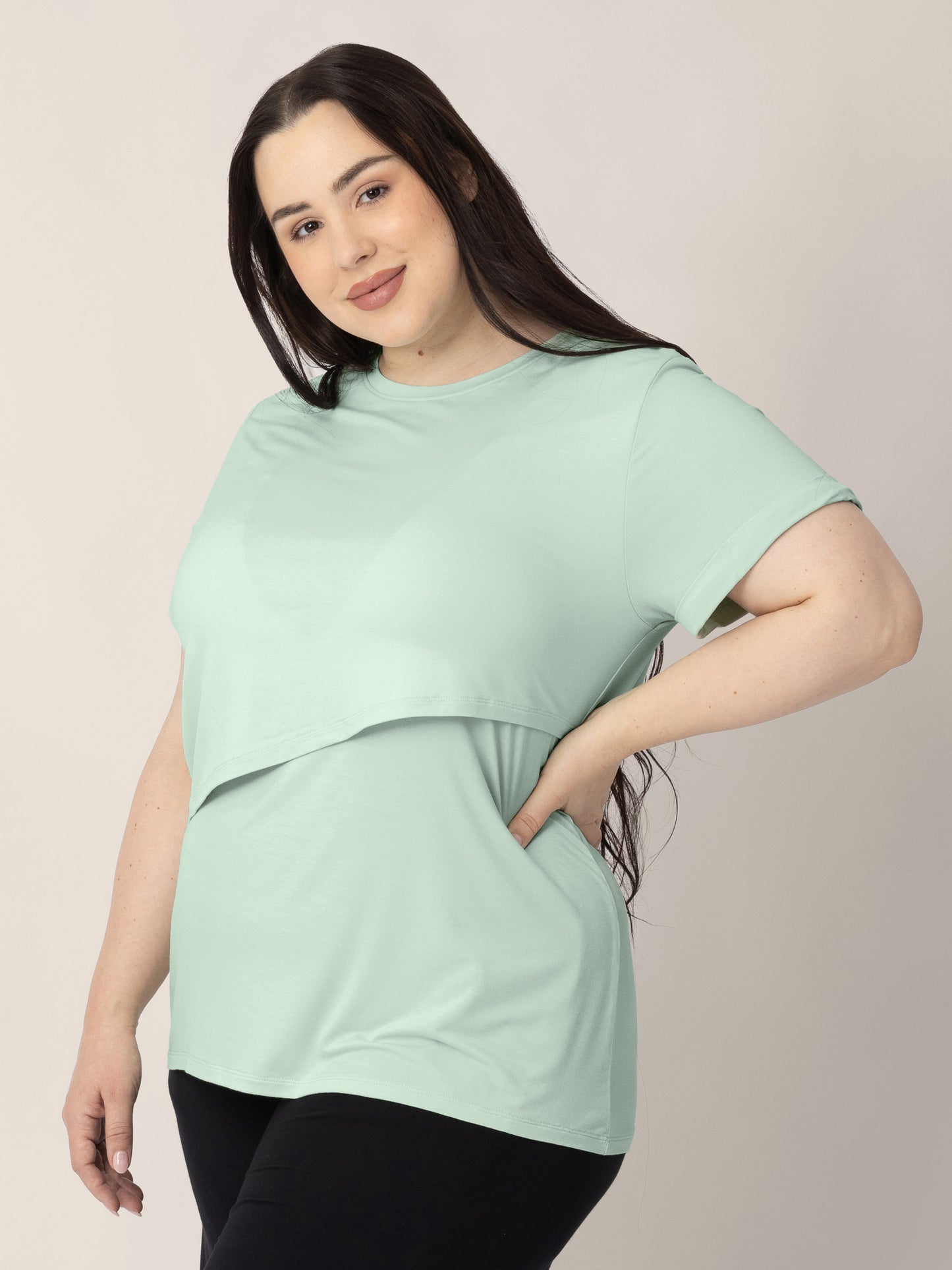 Three-quarters view of a model wearing the Everyday Asymmetrical Nursing T-shirt in Soft Mint.