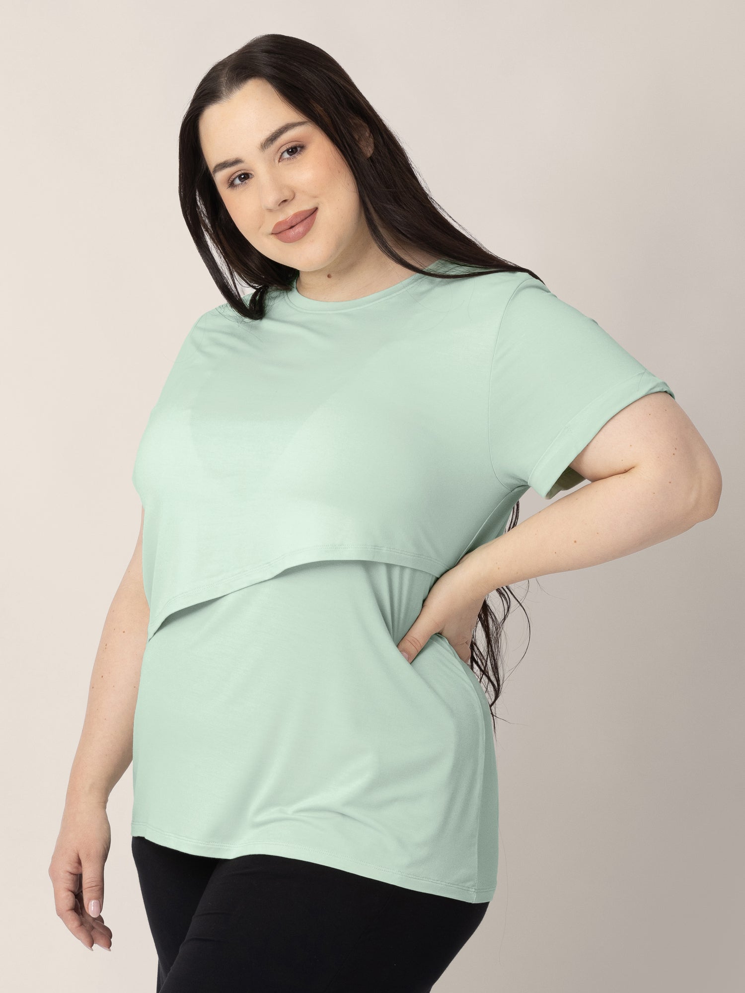 Three-quarters view of a model wearing the Everyday Asymmetrical Nursing T-shirt in Soft Mint.