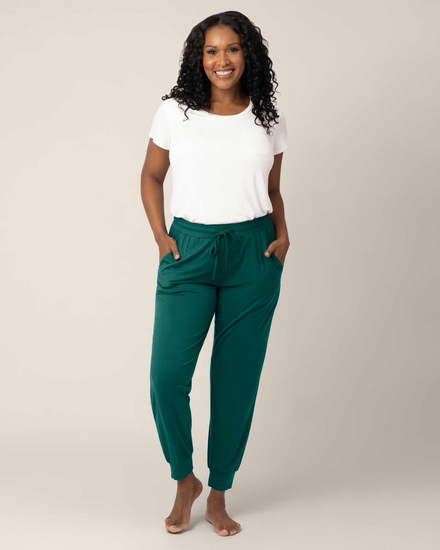 Front view of model wearing the Everyday Lounge Jogger in Evergreen, paired with the Everyday Maternity & Nursing T-shirt in White@model_info:Rashé is 5'6" and wearing a Medium Regular.