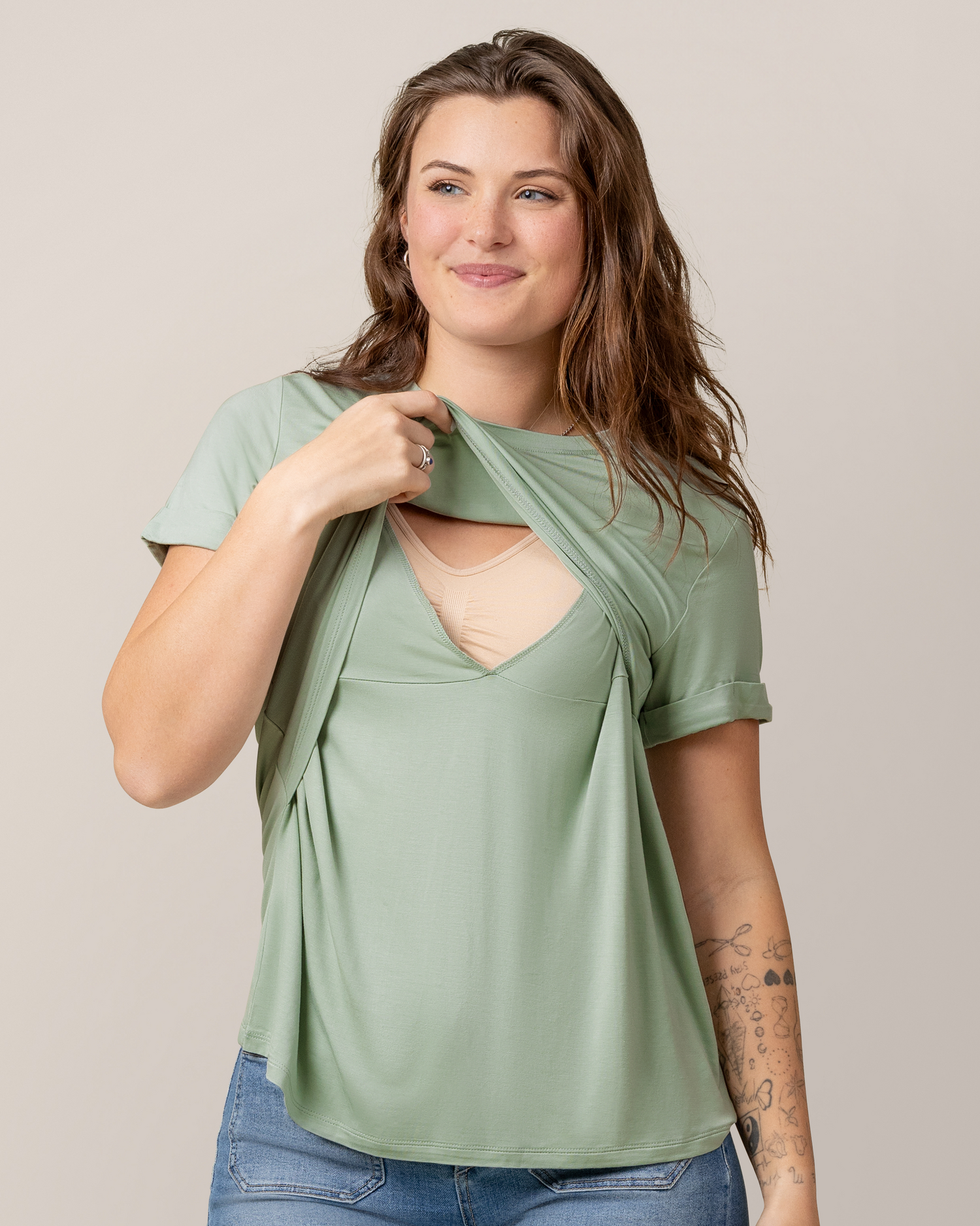 Front view of model wearing the Everyday Asymmetrical Nursing T-shirt in Aqua Mist, pulling up outer layer to show nursing access