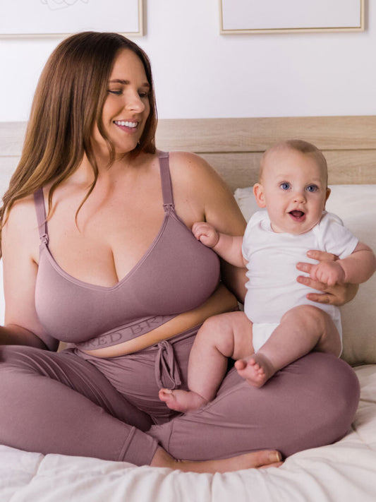 Model wearing the Signature Sublime® Contour Maternity & Nursing Bra in Twilight and holding her baby. @model_info: Ali is wearing a Large Busty.