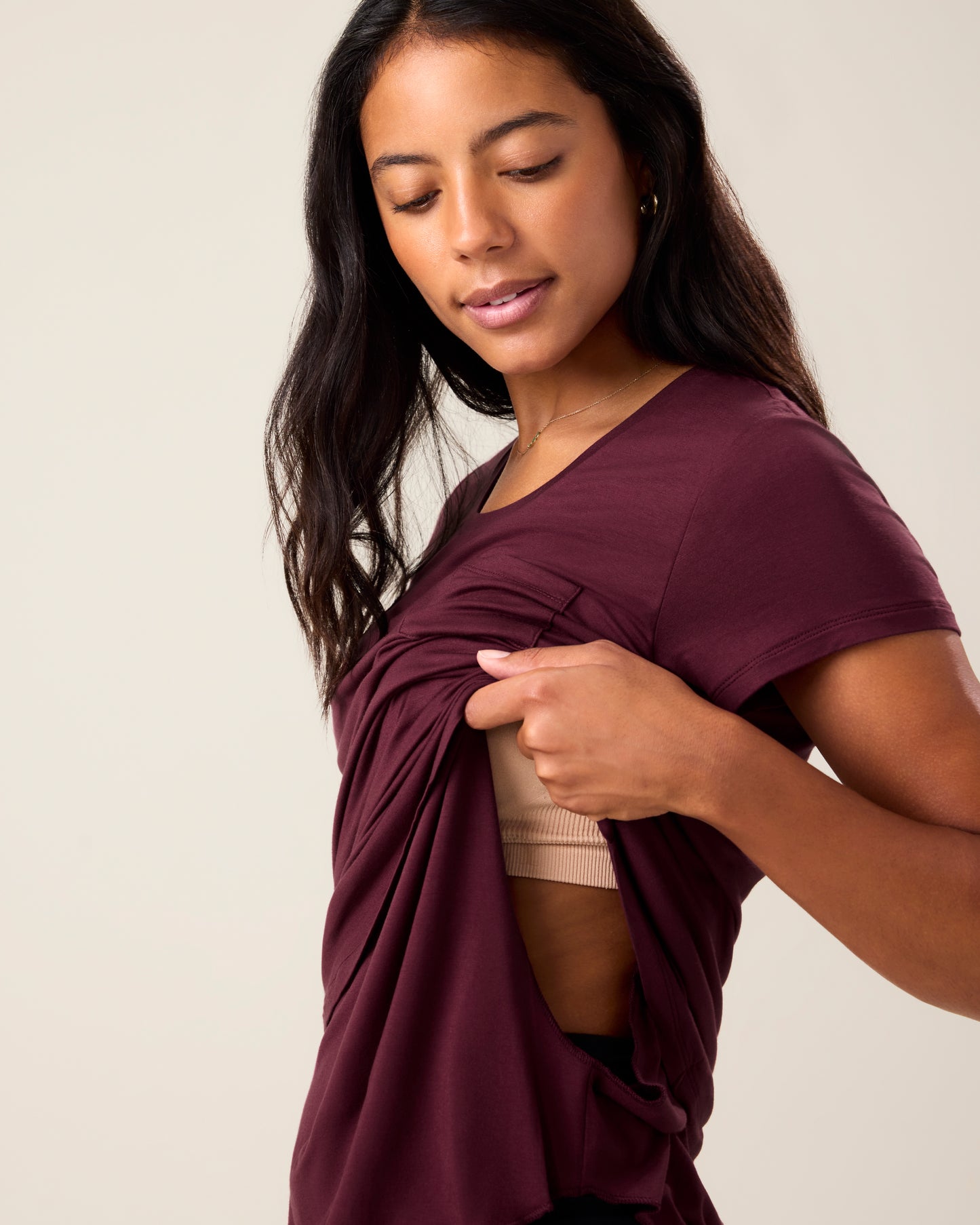 Woman wearing the Everyday Maternity & Nursing T-shirt in Deep Burgundy, lifting outer layer to show nursing access