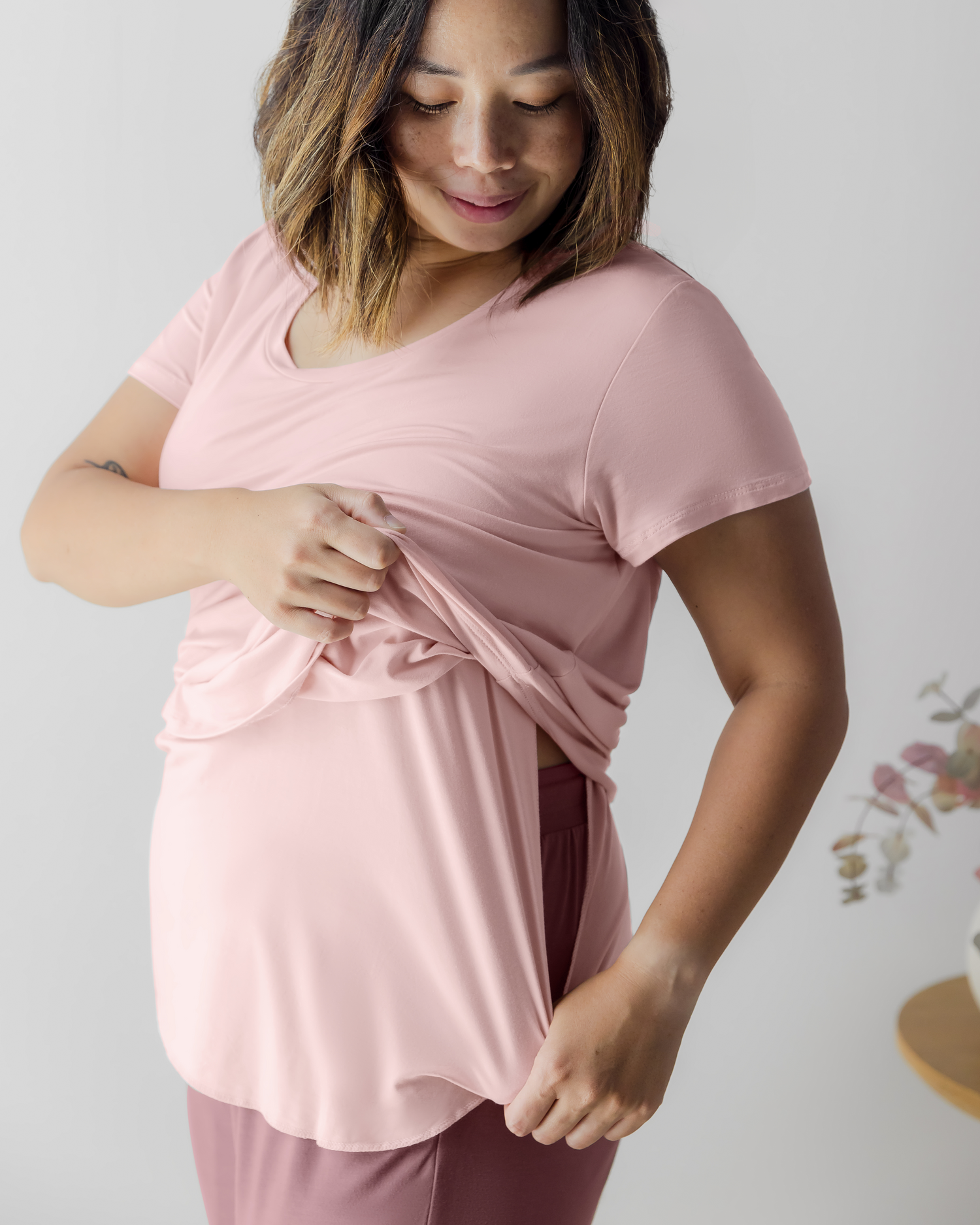 Model wearing the Everyday Maternity & Nursing T-shirt in Dusty Pink, pulling aside layer to show nursing access