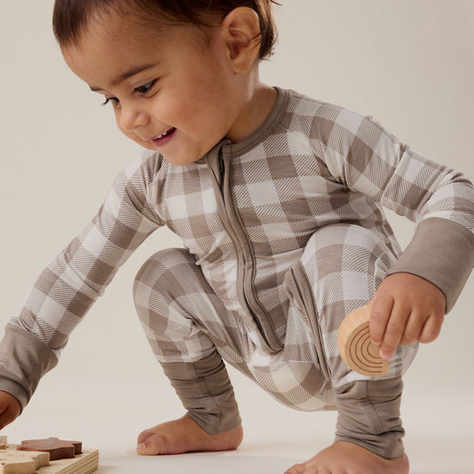 Child playing with wooden toys wearing a gray and white checkered outfit.