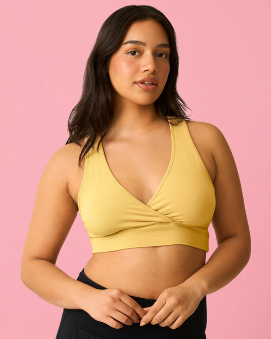 Front view of model wearing French Terry Racerback Nursing & Sleep Bra in Dandelion on a pink background@model_info:Amber is wearing a Medium