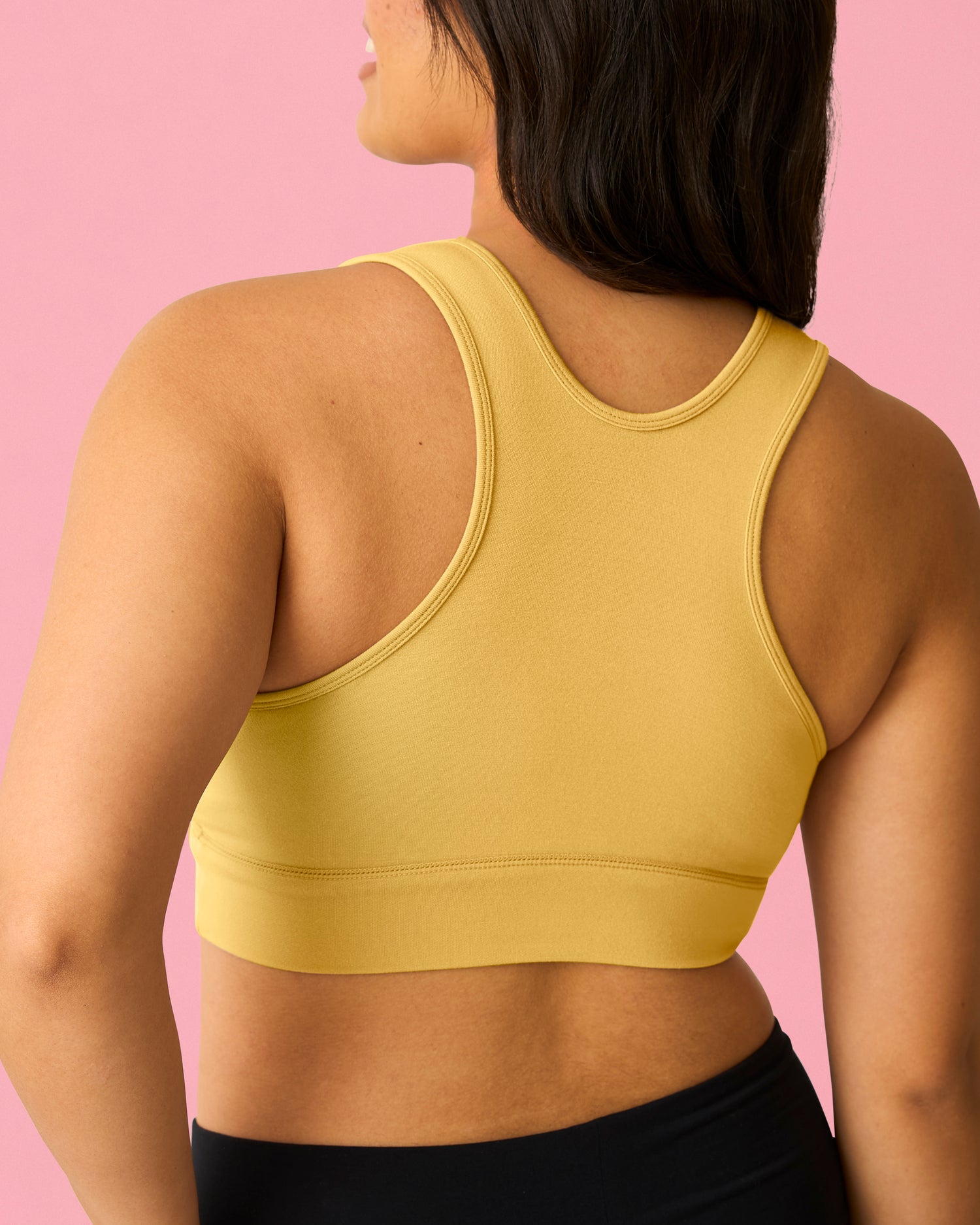 Back view of model wearing French Terry Racerback Nursing & Sleep Bra in Dandelion on a pink background