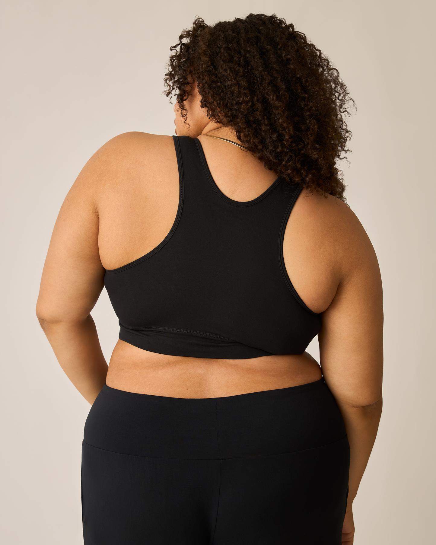 Woman wearing the French Terry Racerback Nursing & Sleep Bra in black against a neutral background, showing racerback