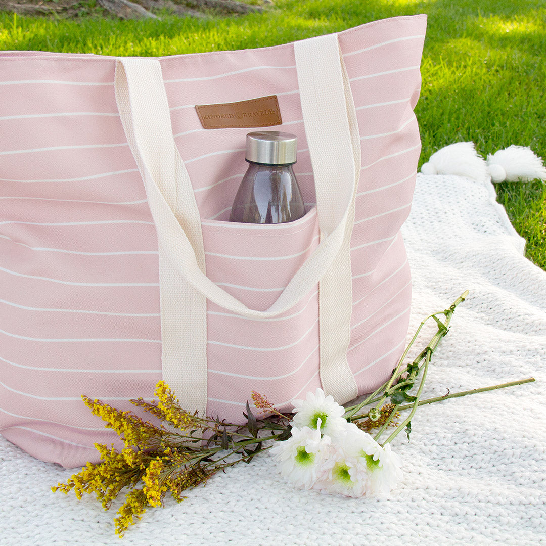 Florence Tote in Pink & White Stripe outside in the sunlight with flowers and a water bottle.